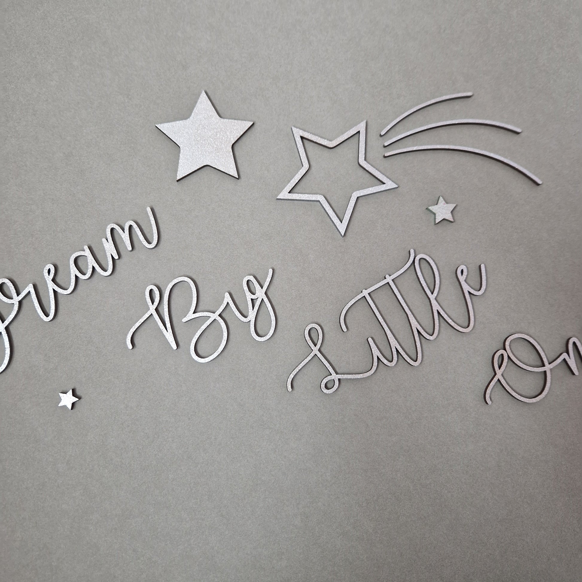 laser cut wooden wall art with the words 'Dream Big Little One' complete with shooting stars and stars painted a colour of your choice.